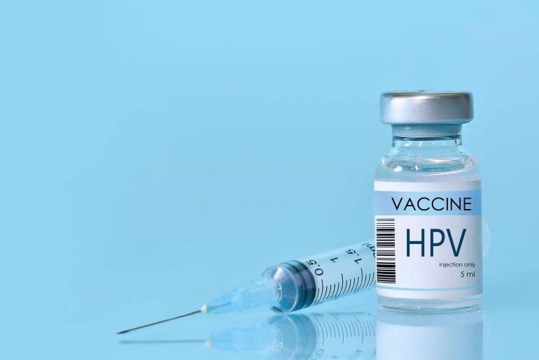 HPV-Impfstoff-Fläschchen und Spritze auf hellblauem Hintergrund.