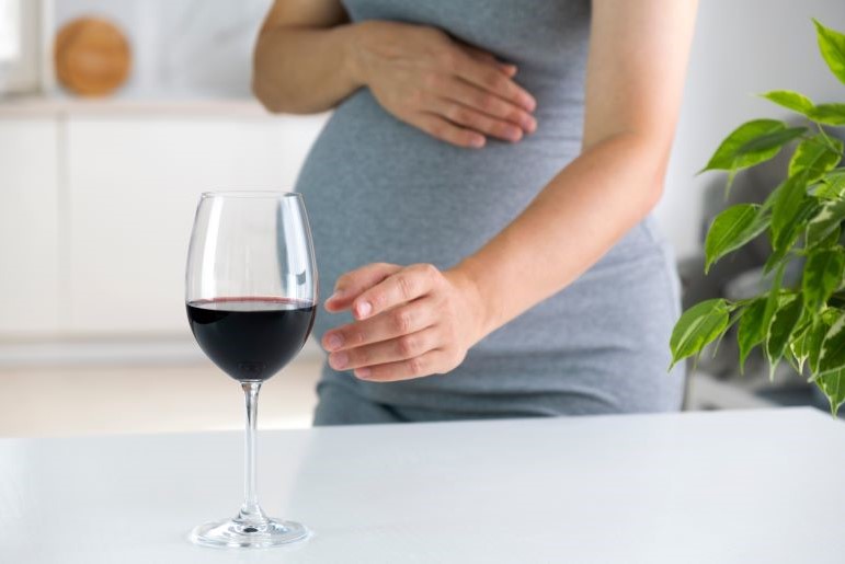 Schwangere greift nach Weinglas; Aufklärung zu Alkohol in der Schwangerschaft und FASD.